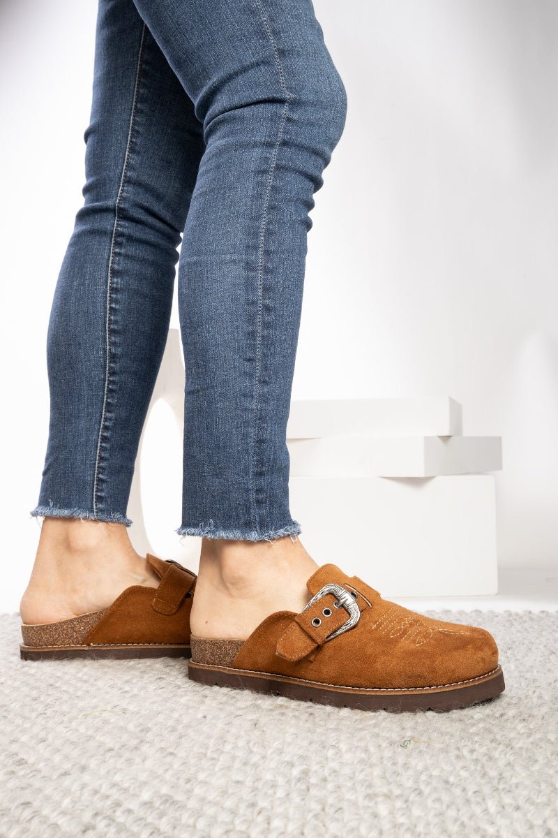 Side View of Brown Clogs on Feet with Frayed Jeans