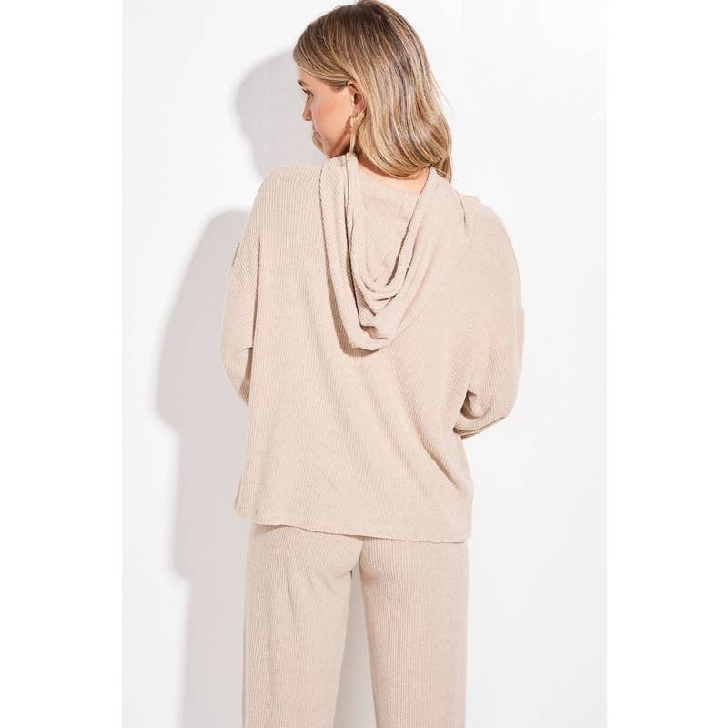 A woman shown from the back wearing a light beige knit lounge set with a draped cowl neckline top and matching pants, against a plain white background.