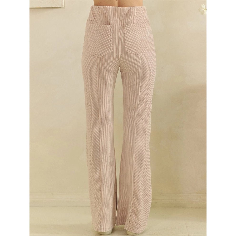 A pair of high-waisted, wide-leg trousers in a light pink corduroy fabric, shown from the back on a model against a neutral beige wall.