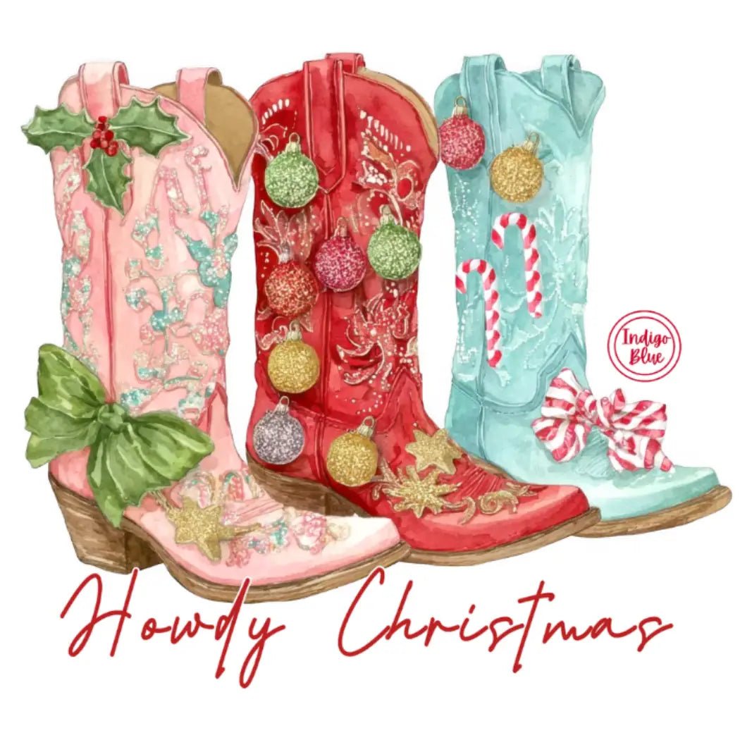 Three decorated cowboy boots in pink, red, and light blue with Christmas ornaments, candy canes, bows, and holly, above the text 'Howdy Christmas' on a white background. A circular 'Indigo Blue' logo appears on the right boot.