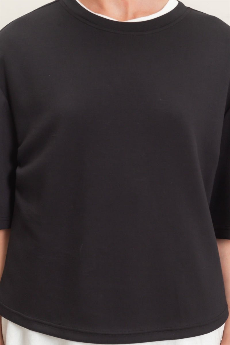 Black t-shirt worn by a person on a plain background