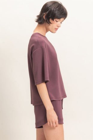 Woman wearing a mauve outfit on a plain background