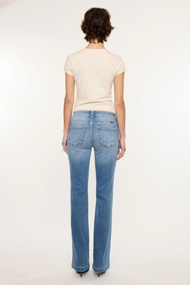 A woman viewed from the back wearing a cream short-sleeve top and light blue straight-leg jeans against a plain white studio background.