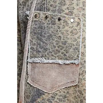 Close-up of a textured patch pocket with a mottled gray and beige patterned upper section, a frayed white lace trim, and a pink-and-white gingham lower section.