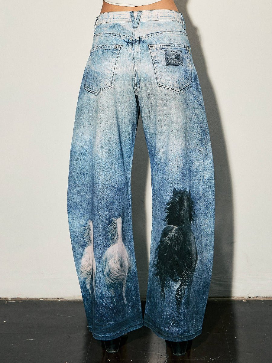 Wide-leg blue denim jeans with a mineral-wash finish, featuring a black dog graphic on the right leg and white dog graphics on the left leg, shown from the back on a model.
