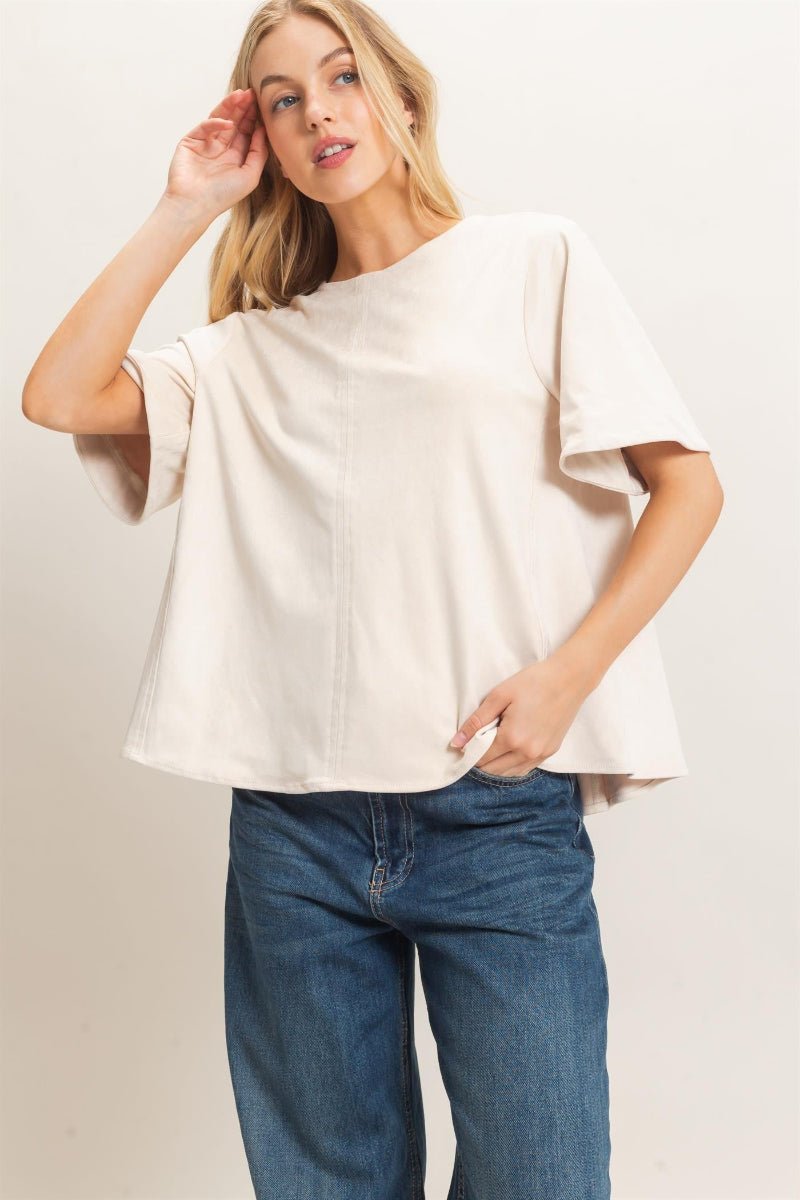 Woman wearing a white top and blue jeans against a plain background