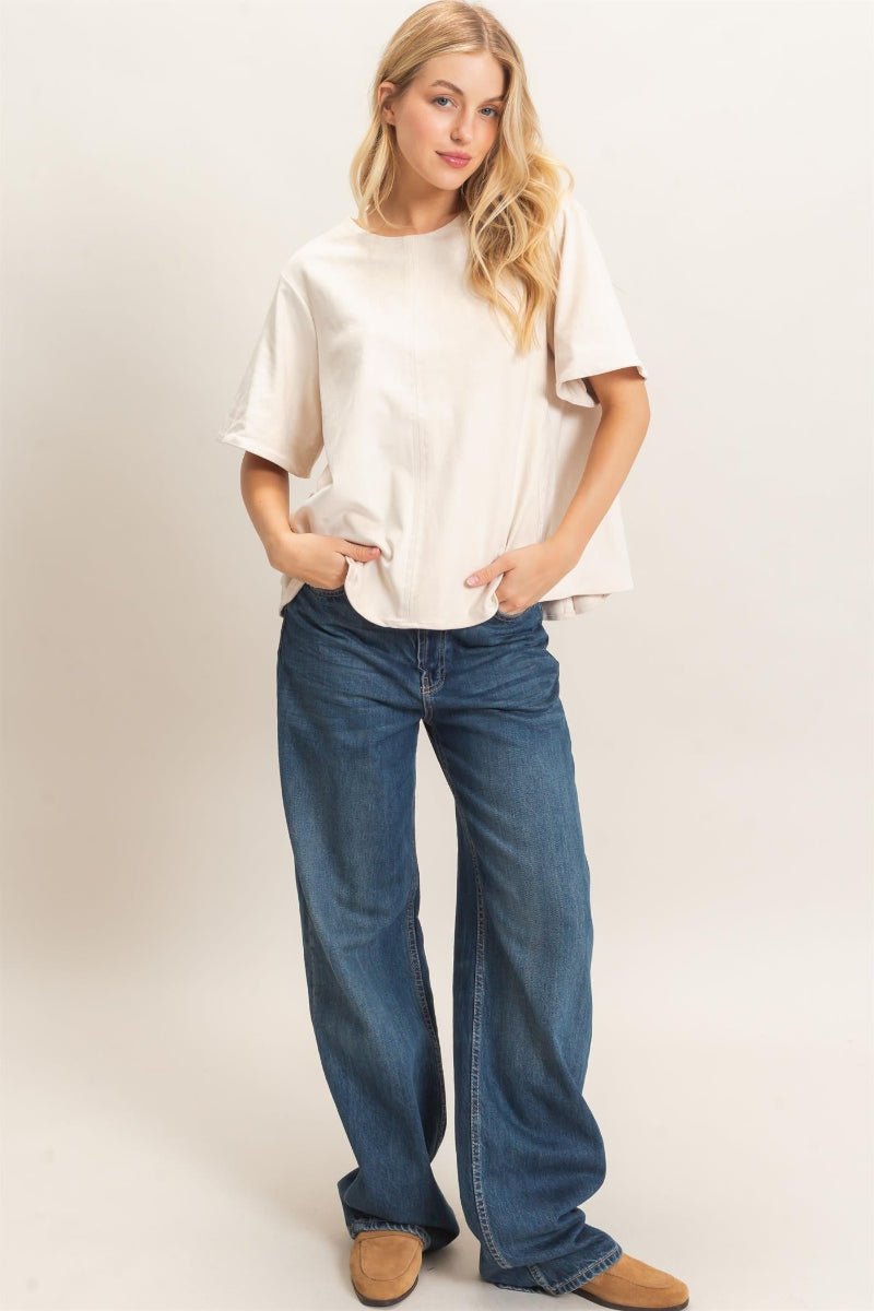 Woman wearing a white t-shirt and blue jeans on a plain background