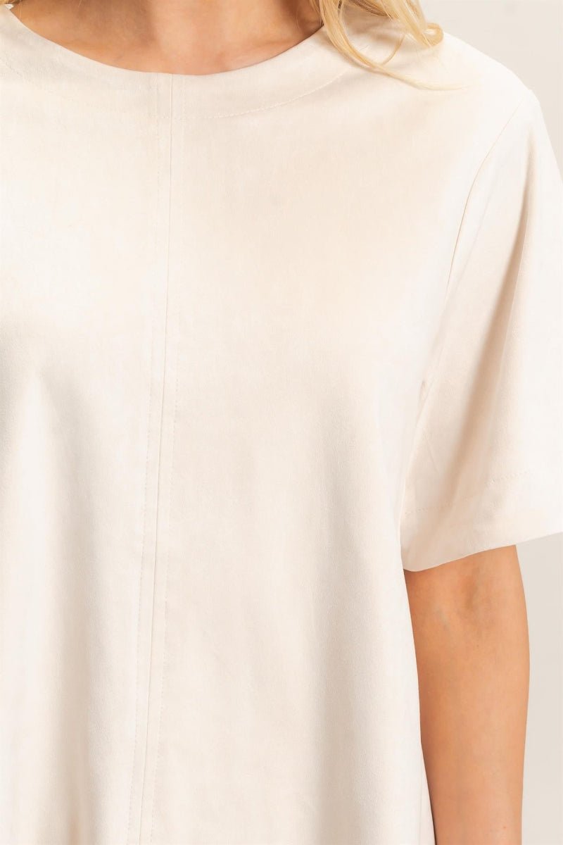 Close-up of a person wearing a plain white shirt against a neutral background