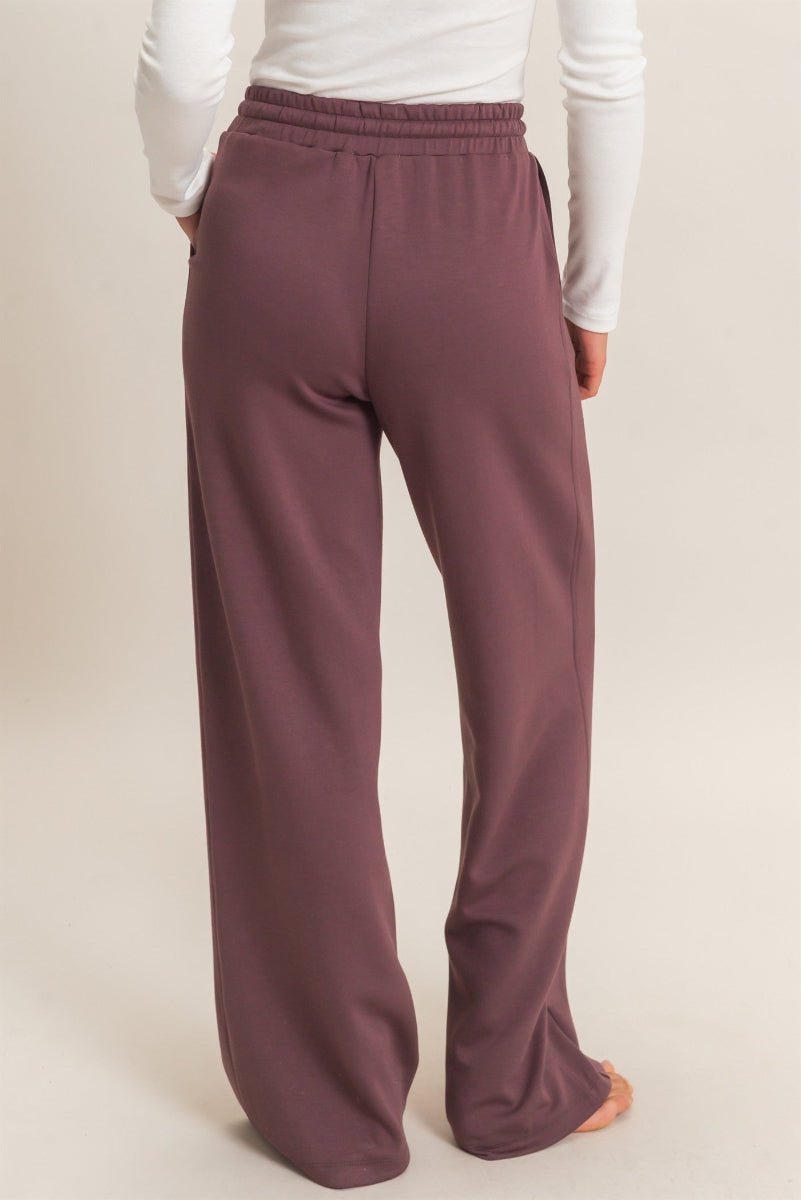 Maroon pants worn by a person on a beige background