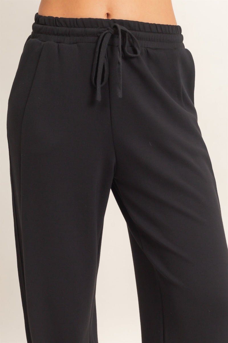 Black pants with a drawstring waist on a beige background
