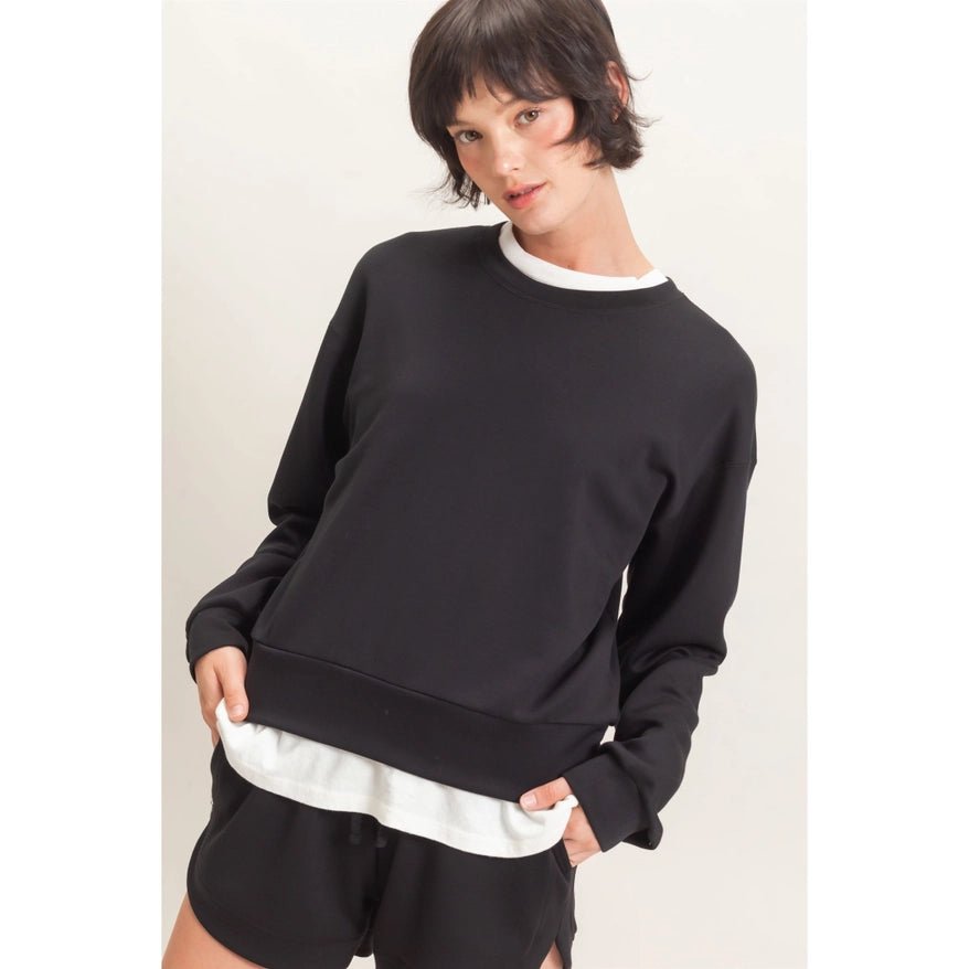 Person wearing a black sweatshirt and shorts on a plain background