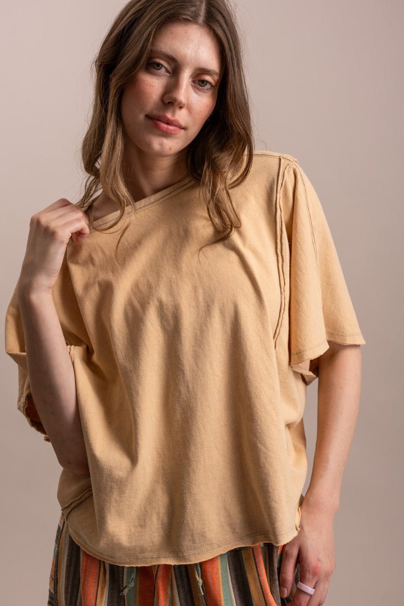 Woman wearing a beige oversized t-shirt against a plain background