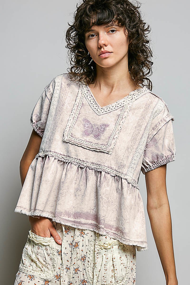 Woman wearing a patterned blouse with a butterfly design on a plain background