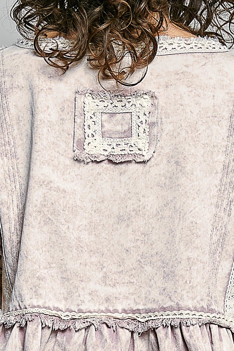 Close-up of a light-colored fabric with lace detailing on a plain background