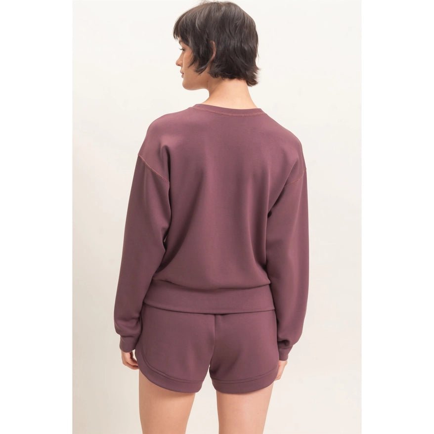 A model shown from the back wearing a matching mauve crewneck sweatshirt and shorts set against a plain off-white background.