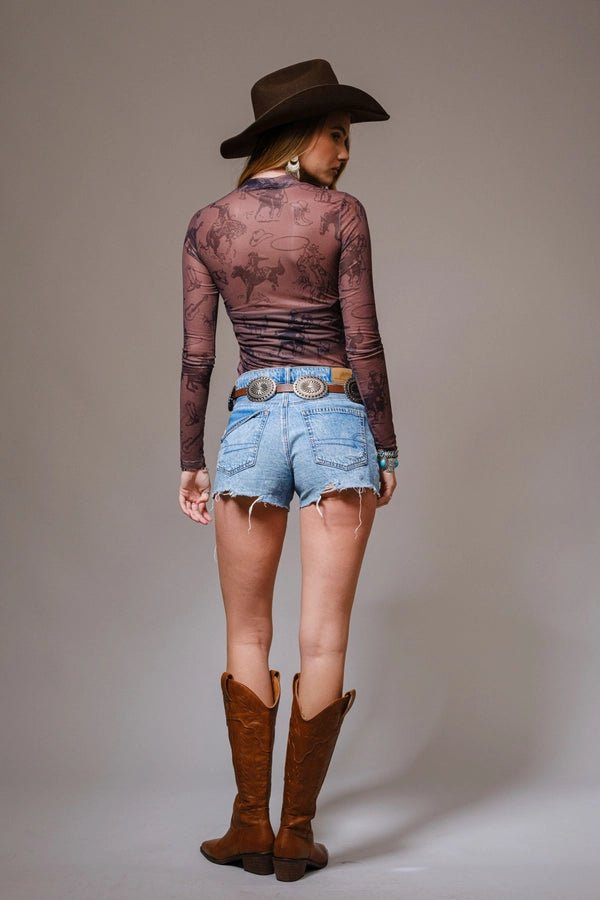 Model Wearing A Mesh Western-Inspired Top Jean Shorts and Boots