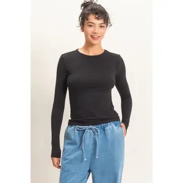 A woman modeling a black long-sleeve crewneck top paired with light blue drawstring pants against a plain off-white background.