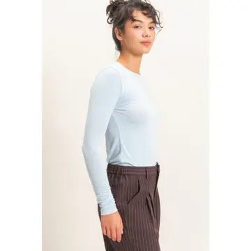 Side view of a woman wearing a light blue top and brown pants