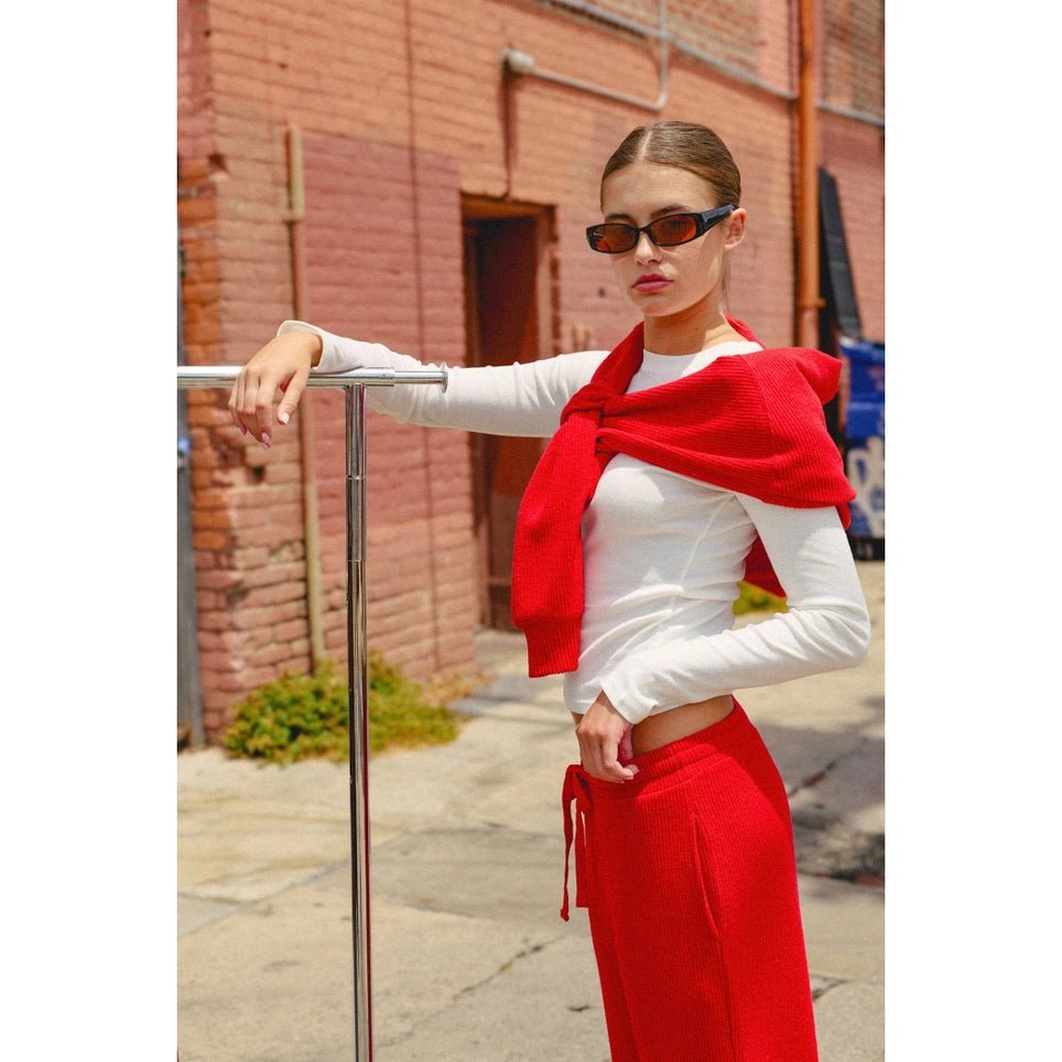 Woman with arm on metal wearing red sweater white top and red joggers