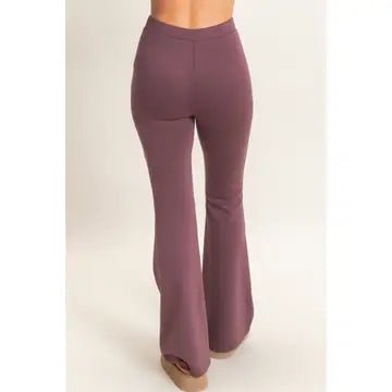 A person wearing high-waisted, flared pants in a muted mauve or dusty rose color, shown from the back against a plain light beige studio background.