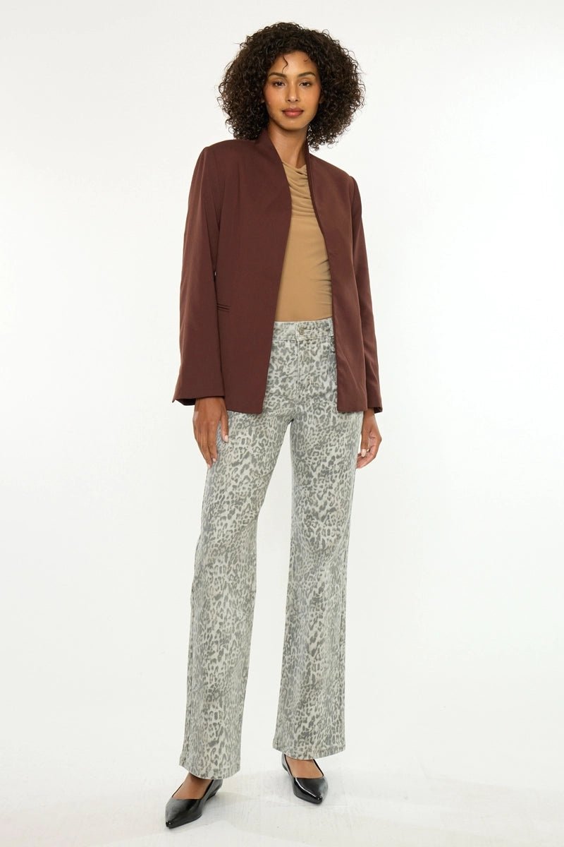 Woman wearing a brown blazer, beige top, and patterned pants on a white background
