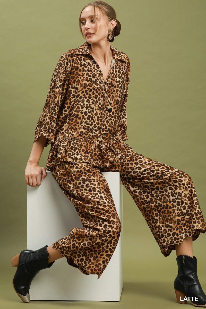 Woman wearing a leopard print outfit sitting on a white block against a green background