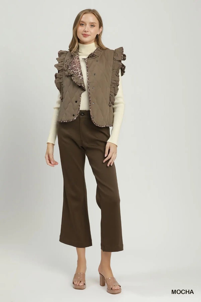 A model stands against a light gray studio background wearing a brown ruffled sleeveless vest over a cream turtleneck, paired with dark brown cropped pants and beige high-heeled sandals. The word 'MOCHA' appears in the bottom right corner.
