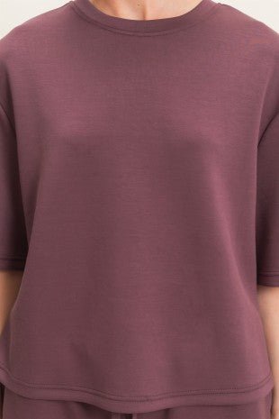 Close-up of a person wearing a plain maroon t-shirt.