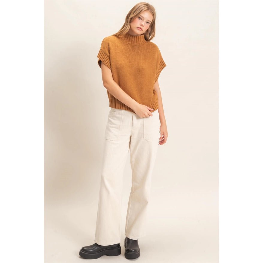 Woman wearing brown sweater cream pants and black shoes