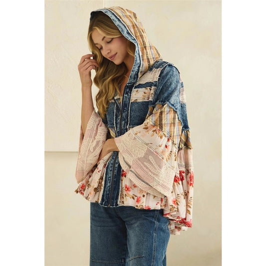 A woman wearing a hooded patchwork top with mixed prints including denim, floral, and plaid, paired with blue jeans, set against a neutral beige background.