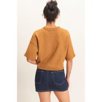 Back view of female wearing a camel color sweater and dark jean skirt