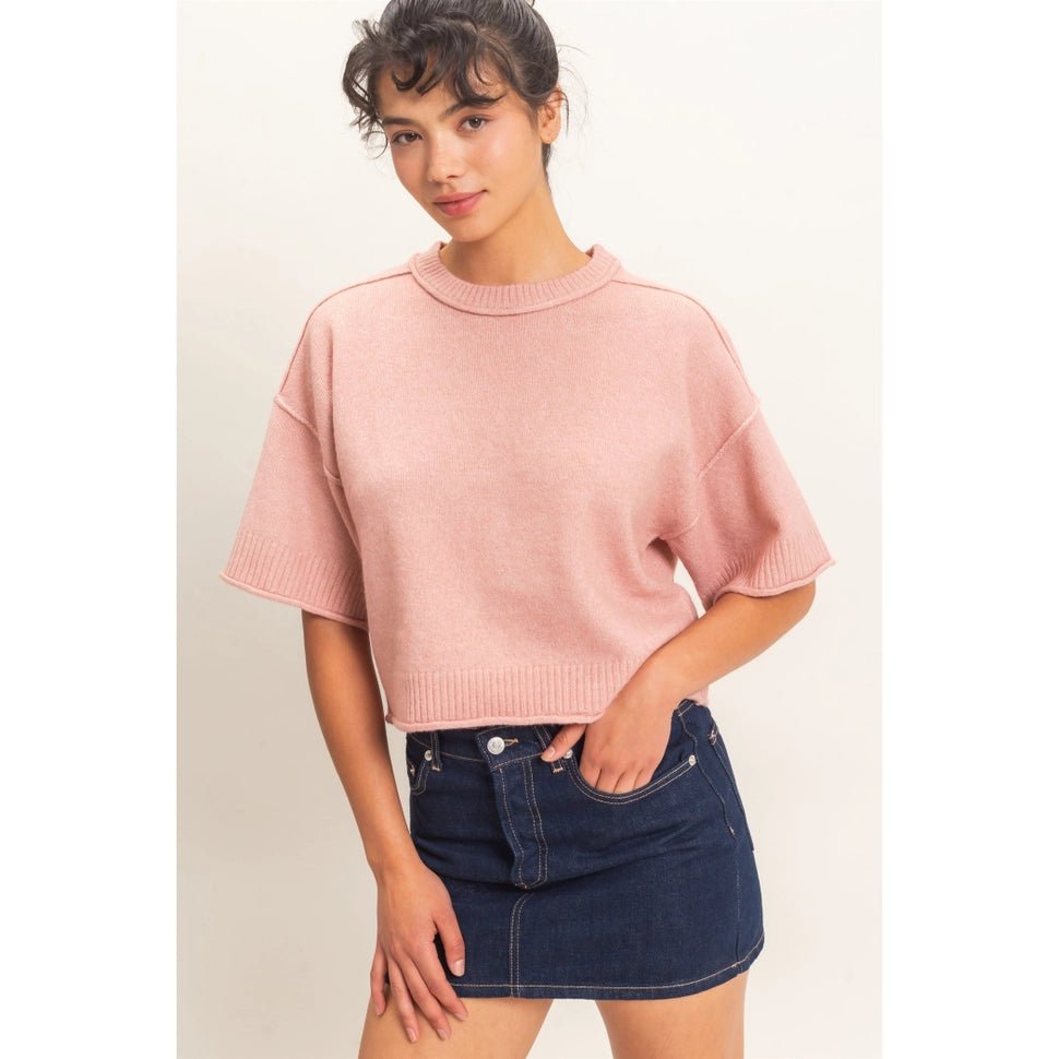 Woman wearing a pink sweater and short dark blue denim skirt