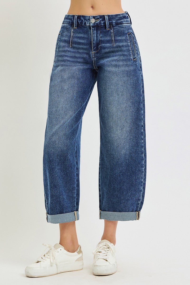 A person wearing blue wide-leg cropped jeans with rolled cuffs and white sneakers, shown from the waist down against a plain light background.