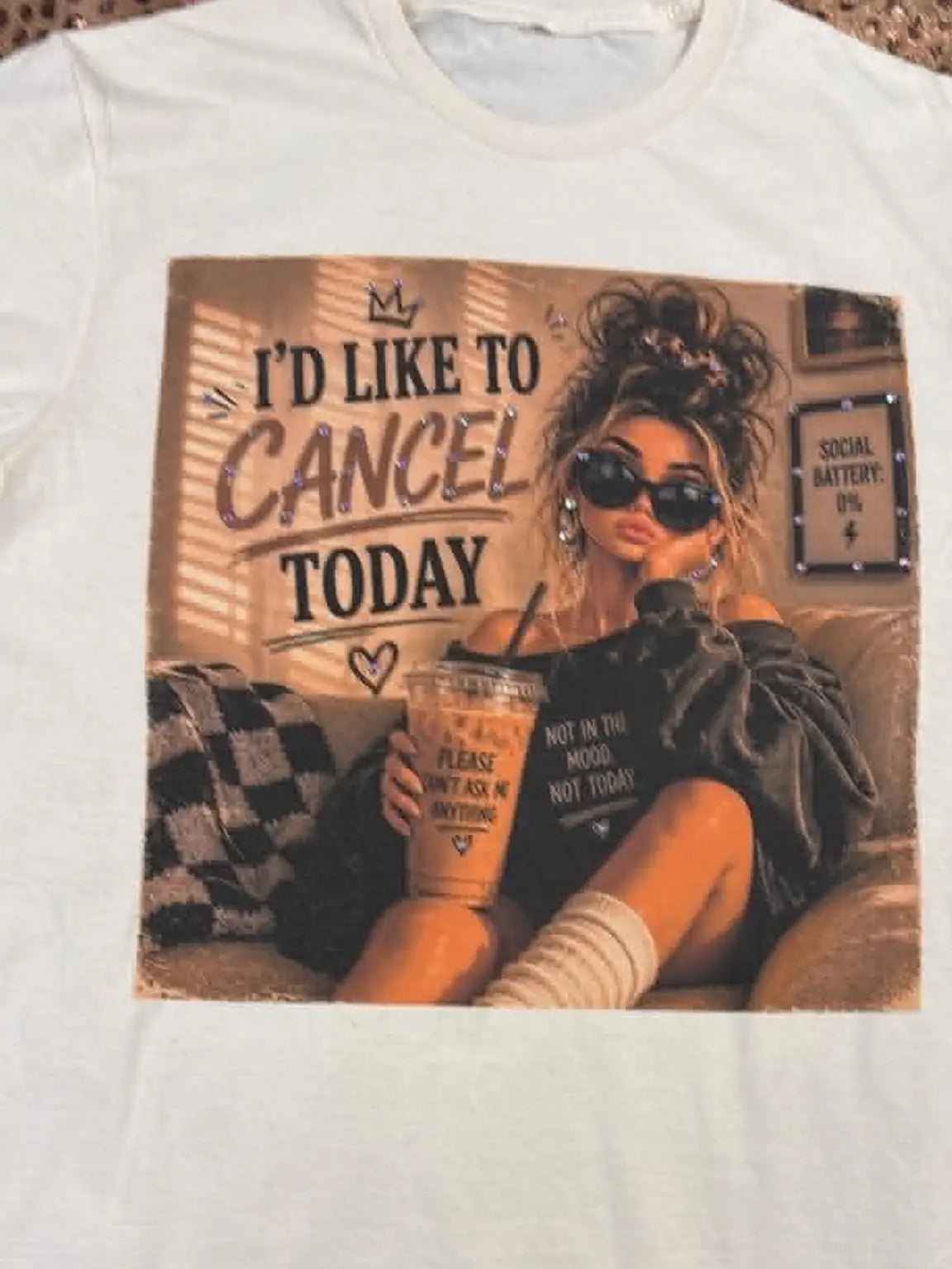 White short-sleeve graphic t-shirt featuring a large square print of a woman in sunglasses holding an iced coffee with the text 'I'D LIKE TO CANCEL TODAY'.