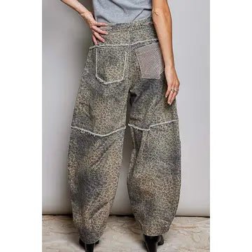 A person wearing loose, wide-leg harem-style pants with a mottled gray and beige pattern, shown from the waist down against a plain light gray wall.