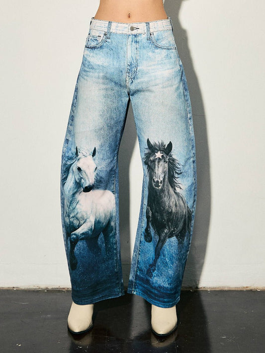 A person wearing wide-leg blue jeans with printed images of a white horse on the left leg and a black horse on the right leg, paired with off-white pointed shoes against a plain light wall.