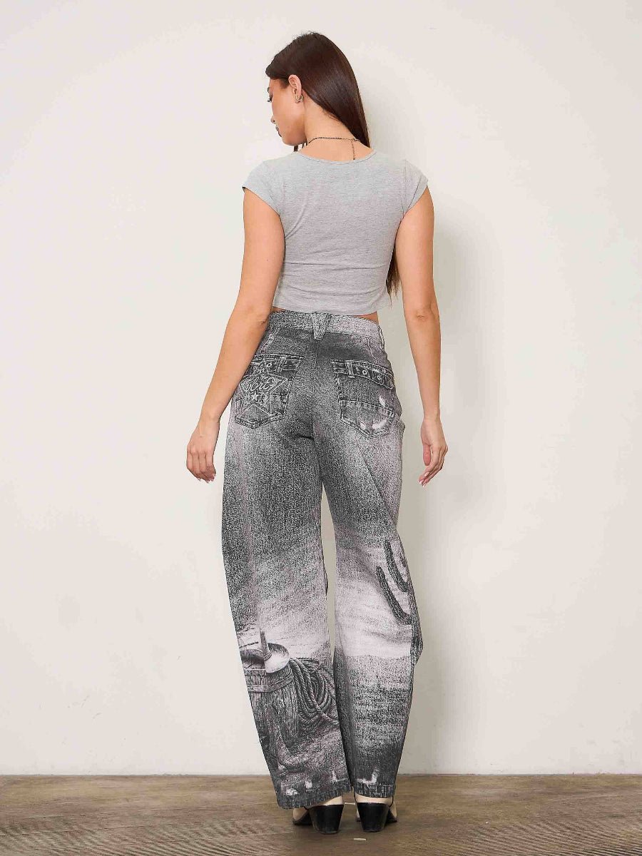 A woman shown from the back wearing a light gray short-sleeve crop top and high-waisted, wide-leg gray jeans with a distressed wash and graphic print details, standing against a plain off-white wall.