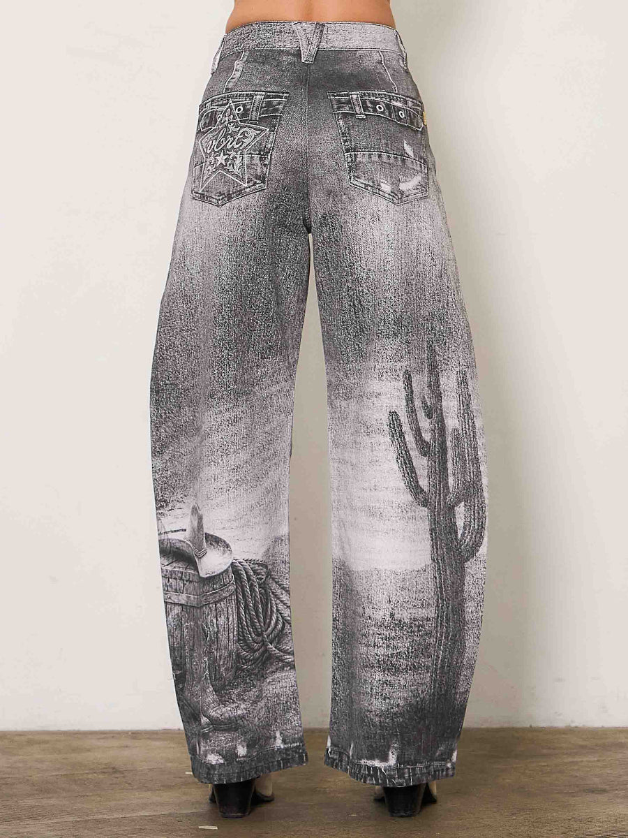 Wide-leg gray denim jeans with a distressed wash and a printed desert landscape design featuring a cactus and a cowboy boot, shown from the back on a model.