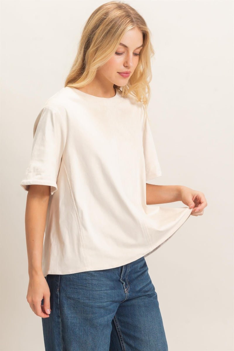Woman wearing a white oversized shirt and blue jeans on a plain background