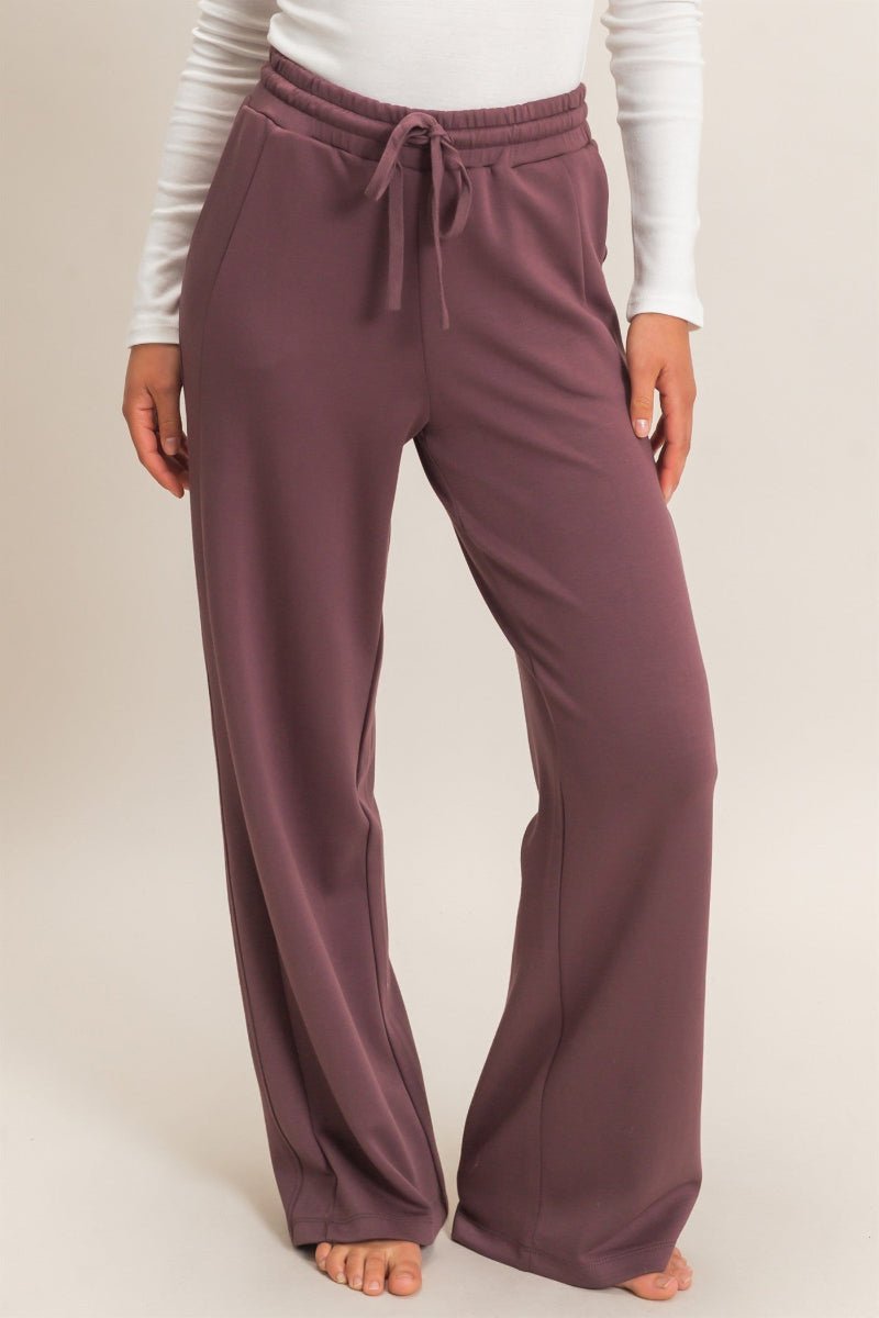 Purple lounge pants worn by a person on a plain background