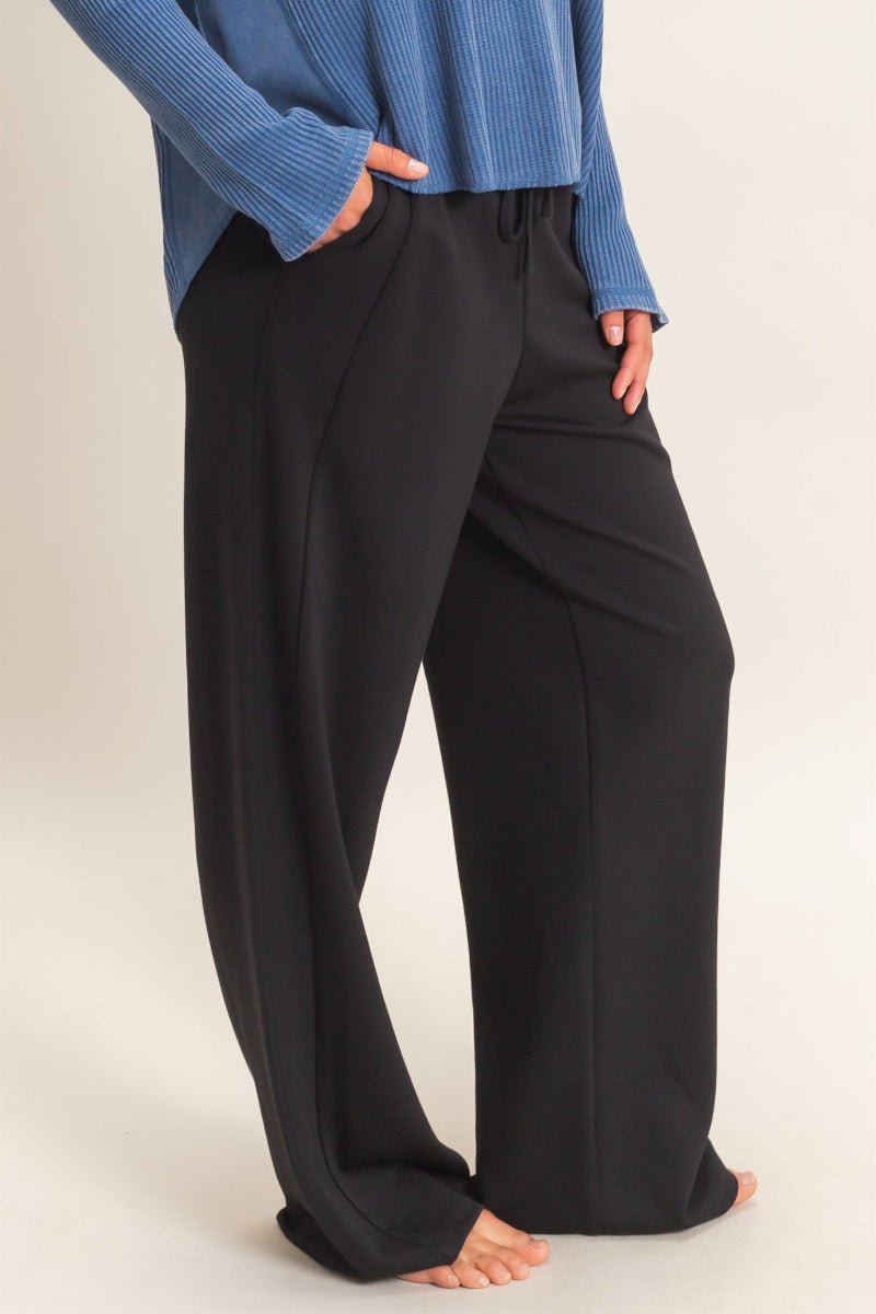 Person wearing black pants and a blue top on a white background